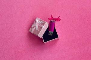 la tarjeta de memoria flash usb rosa brillante con un lazo rosa se encuentra en una pequeña caja de regalo en rosa con un pequeño lazo sobre una manta de suave y peluda tela de vellón rosa claro. diseño clásico de tarjeta de memoria de regalo femenino foto