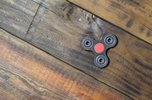 A rare handmade wooden fidget spinner lies on a brown wooden background surface. Trendy stress relieving toy photo