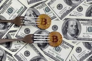 Bitcoin getting New Hard Fork Change, Physical Golden Crytocurrency Coin under the fork on the dollars background. Blockchain Transaction System Crisis Concept photo