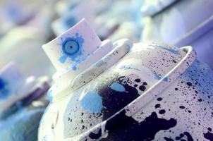 A lot of dirty and used aerosol cans of bright blue paint. Macro photograph with shallow depth of field. Selective focus on the spray nozzle photo