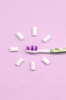 Toothbrush and chewing gums lie on a pastel pink background photo