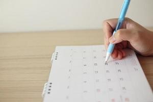 Hand with pen writing on calendar date photo