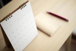 calendar page close up on wood table background with pen and notebook business planning appointment meeting concept photo