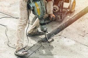 Construction worker using jackhammer drilling concrete surface photo