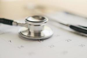 Stethoscope with calendar page date on wood table background doctor appointment medical concept photo