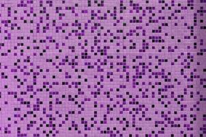 The texture of the wall, decorated with a mosaic of various small square tiles. Abstract pattern of ceramic tiles on the wall photo