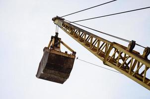 Old yellow mechanical clamshell grab on blue sky background photo