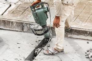 trabajador de la construcción con martillo perforador de superficie de hormigón foto