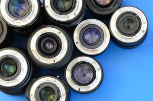 Several photographic lenses lie on a bright blue background. Space for text photo