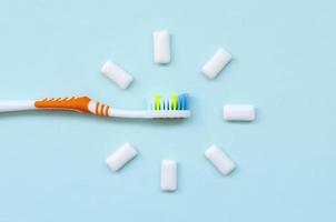 Toothbrush and chewing gums lie on a pastel blue background. Top view, flat lay. Minimal concept photo