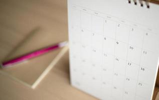 calendar page close up on wood table background with pen and notebook business planning appointment meeting concept photo