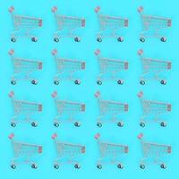 Shopping addiction, shopping lover or shopaholic concept. Many small empty shopping carts perform a pattern on a pastel colored paper background. Flat lay composition, top view photo