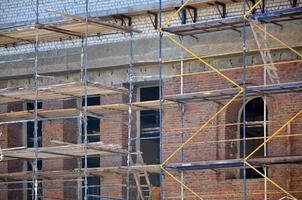 Scaffolds installed near the multi-storey brick building under construction photo