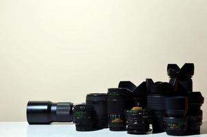 Many different professional lenses for SLR camera lies on a colorless desk photo