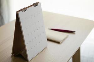 página del calendario de cerca en el fondo de la mesa de madera con bolígrafo y cuaderno concepto de reunión de cita de planificación empresarial foto