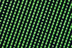 Macro shot of a glitch on the monitor of an office computer. The concept of introducing a virus into a personal data keeper. Stream of random green symbols on a black background photo