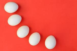 A few white eggs on a bright red background photo