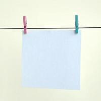 White blank cards on rope, light wall background. Creative reminder, small sheets of paper on old clothespin, memo backdrop photo