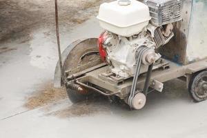 trabajador que utiliza una máquina de hoja de sierra de diamante cortando una carretera de hormigón en el sitio de construcción foto