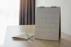 página del calendario de cerca en el fondo de la mesa de madera con lápiz y cuaderno concepto de reunión de cita de planificación empresarial foto