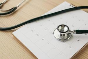 Stethoscope with calendar page date on wood table background doctor appointment medical concept photo