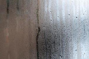 Texture of a drop of rain on a glass wet transparent background. Toned in grey color photo