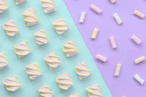 Colorful marshmallow laid out on violet and blue paper background. pastel creative textured pattern. minimal photo