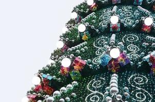 A fragment of a huge Christmas tree with many ornaments, gift boxes and luminous lamps. Photo of a decorated Christmas tree close-up with copy space