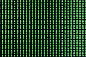 Macro shot of a glitch on the monitor of an office computer. The concept of introducing a virus into a personal data keeper. Stream of random green symbols on a black background photo