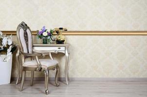 A fragment of a retro interior with a chair and a desk on which is located a telephone and a vase of flowers photo