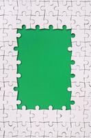 Framing in the form of a rectangle, made of a white jigsaw puzzle around the green space photo