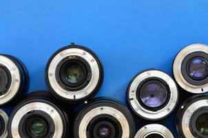 Several photographic lenses lie on a bright blue background. Space for text photo