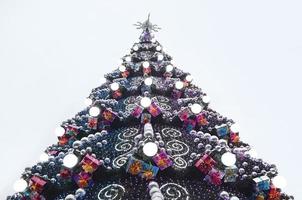 un fragmento de un enorme árbol de navidad con muchos adornos, cajas de regalo y lámparas luminosas. foto de un primer plano de árbol de Navidad decorado con espacio de copia