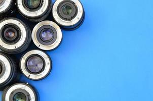 Several photographic lenses lie on a bright blue background. Space for text photo