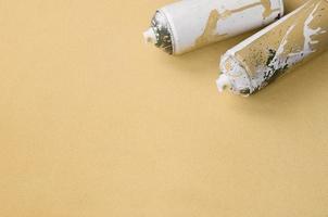 algunas latas de aerosol naranja usadas con gotas de pintura se encuentran sobre una manta de tela suave y peluda de color naranja claro. color de diseño de moda clásico. concepto de vandalismo de graffiti foto