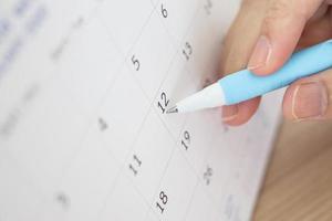 Hand with pen writing on calendar date photo