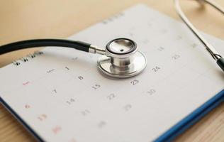 estetoscopio con fecha de página de calendario en el fondo de la mesa de madera concepto médico de cita médica foto