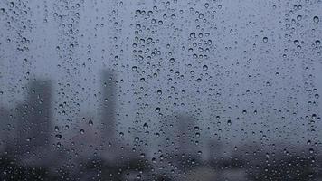 images de gouttes de pluie sur une fenêtre en verre avec un arrière-plan flou de la ville. video