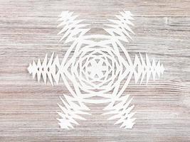 snowflake cut out of paper on light brown plank photo