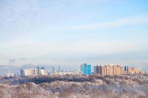 white clouds in blue sky over snow forest and town photo