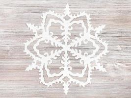 snowflake cut out of paper on light brown surface photo