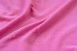 The blanket of furry pink fleece fabric. A background of light pink soft plush fleece material with a lot of relief folds photo