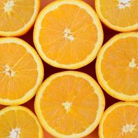 Top view of a several orange fruit slices on bright background in orange color. A saturated citrus texture image photo