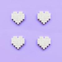 A few hearts made of sugar cubes lies on a trendy pastel violet background photo