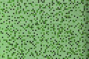 The texture of the wall, decorated with a mosaic of various small square tiles. Abstract pattern of ceramic tiles on the wall photo