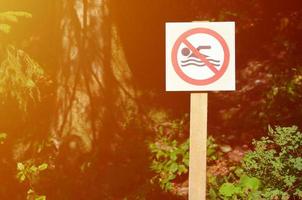 A pillar with a sign denoting a ban on swimming. The sign shows a crossed-out floating person photo