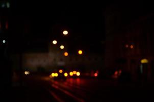 escena nocturna borrosa de tráfico en la carretera. imagen desenfocada de coches que viajan con faros luminosos. arte bokeh foto