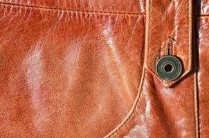 Brown leather texture. Useful as background for any design work. Macro photo of a button on outer clothing made of genuine leather