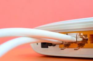 The Internet cable plugs are connected to the Internet router, which lies on a bright orange background. Items required for Internet connection photo