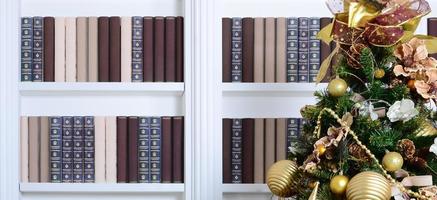A beautiful decorated Christmas tree on the background of a bookshelf with many books of different colors. Christmas background image of the library photo